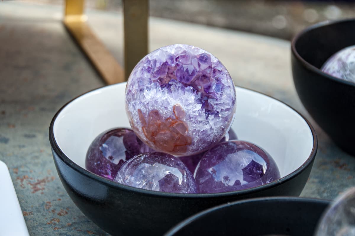 Decorative purple sphere in a black bowl on a textured surface