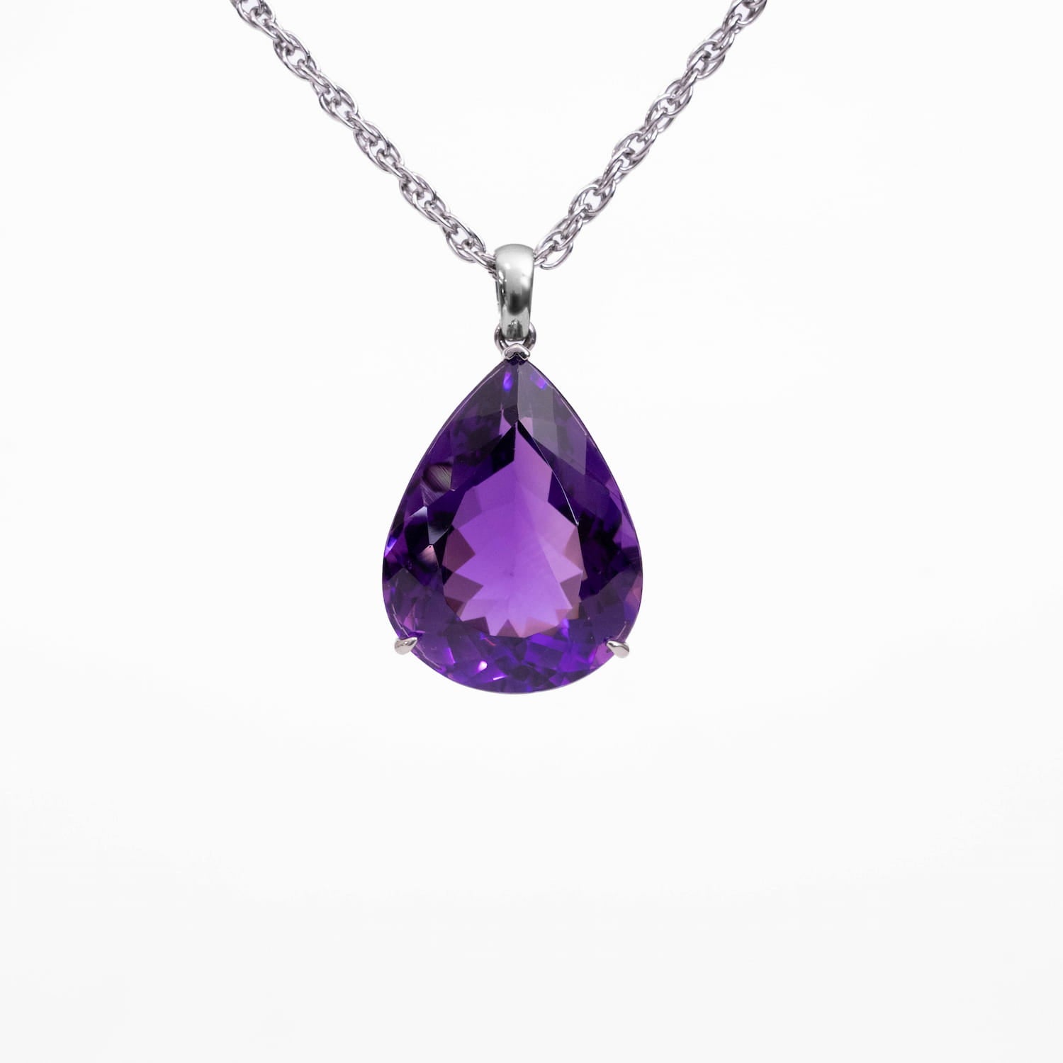 A teardrop-shaped purple Amethyst gemstone pendant necklace in a silver setting on a delicate silver chain, shown against a plain white background.