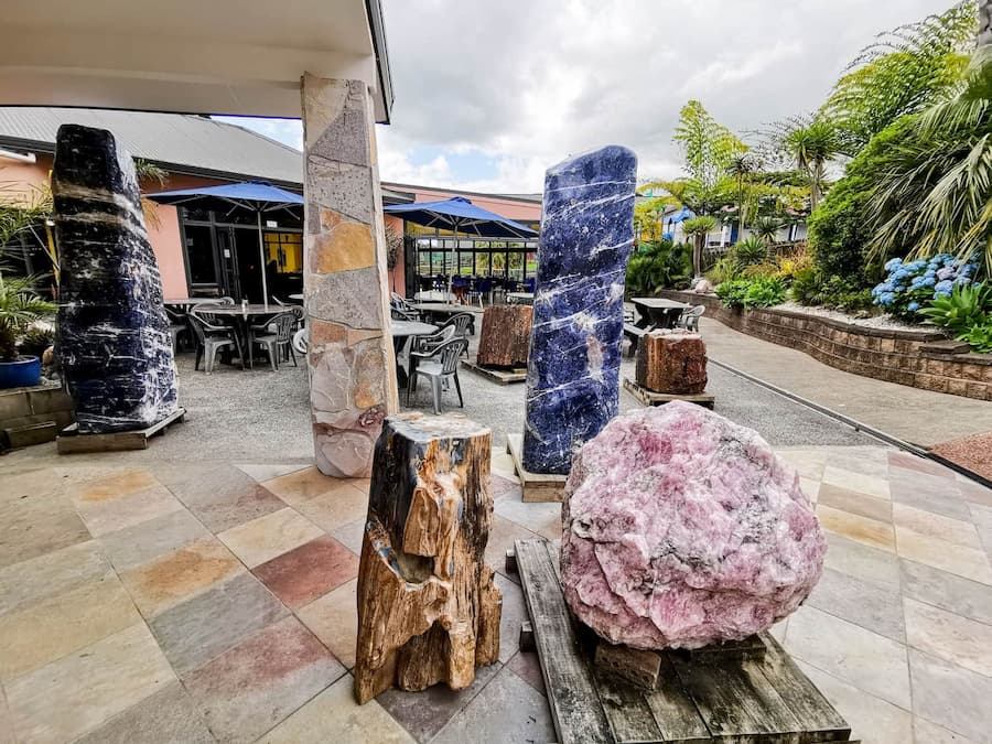 Decorative stones and sculptures on a patio with a building and outdoor furniture in the background.