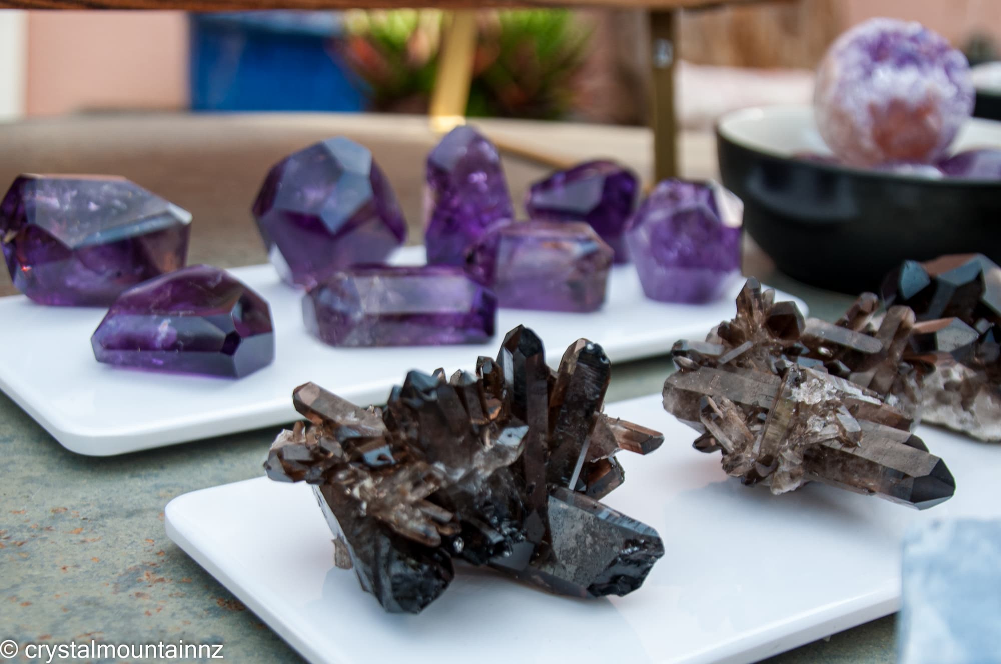 Smoky Quartz clusters and Amethyst crystals on a white surface with blurred background