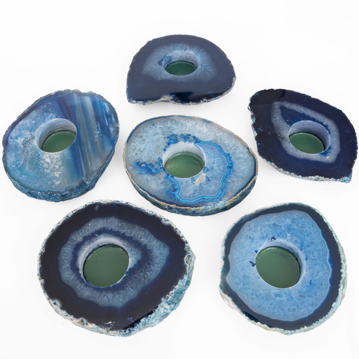 Six blue agate slice coasters arranged on a plain white background. Each coaster is made from a polished natural agate slice with concentric bands of dark navy, bright blue, and pale icy blue, with a greenish translucent center hole.