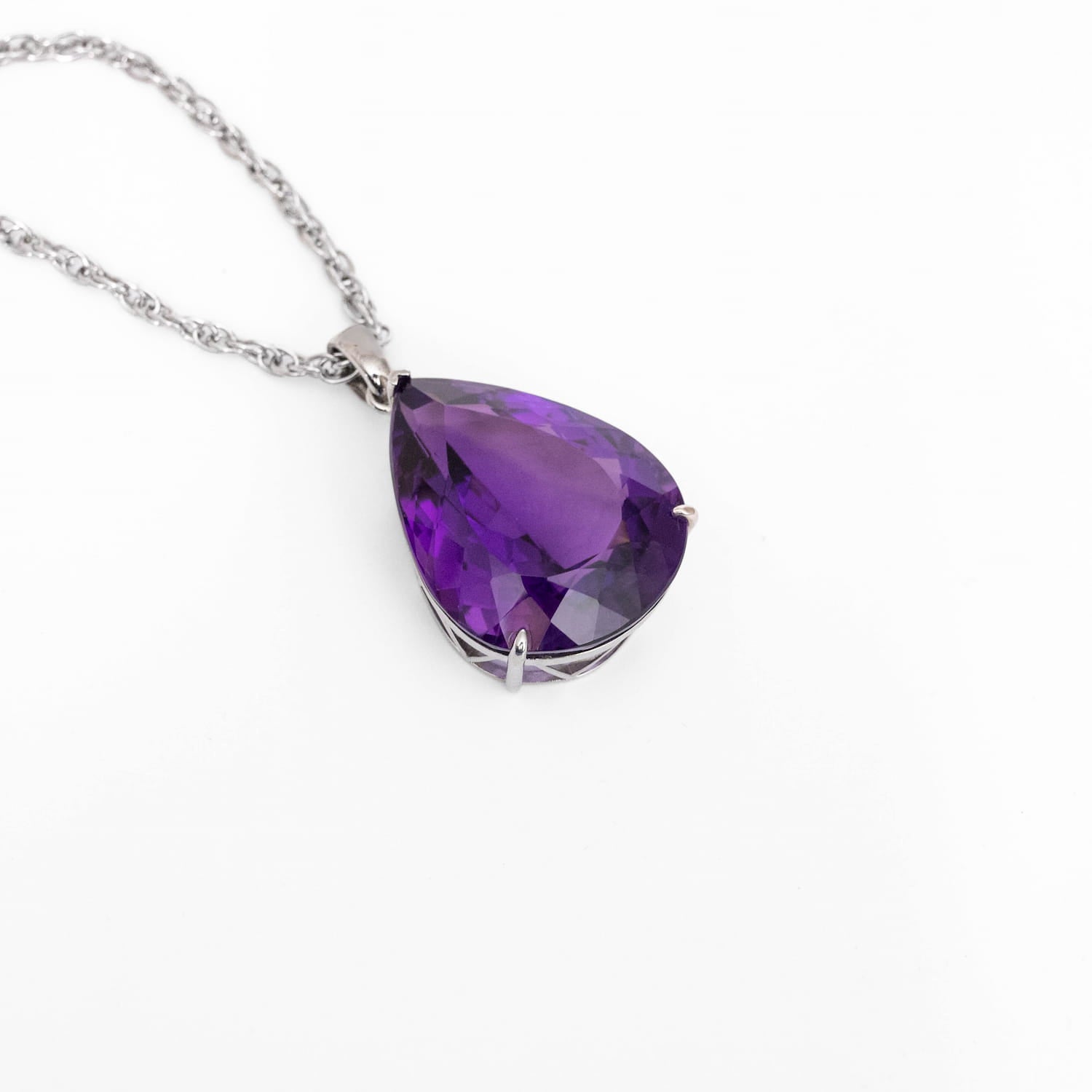 A teardrop-shaped purple Amethyst gemstone pendant on a silver chain, displayed on a clean white background.