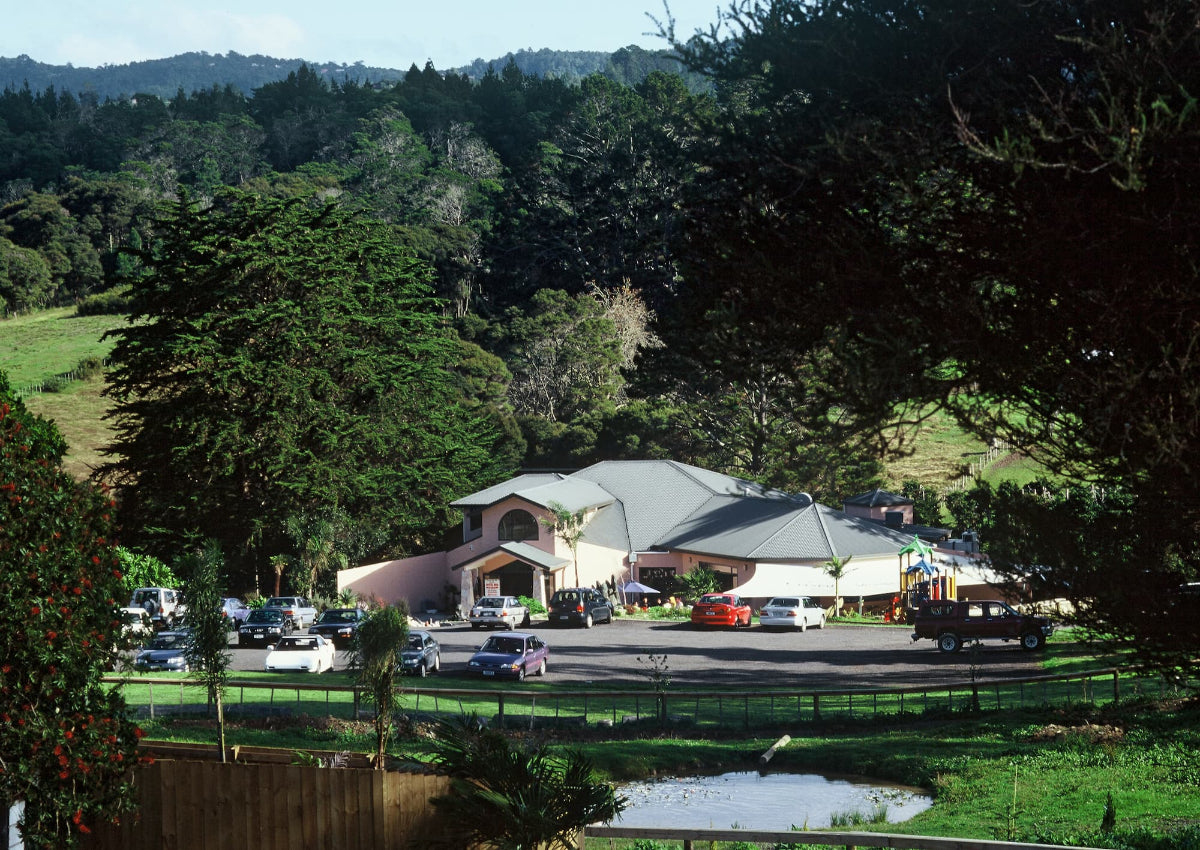 Building with a green roof surrounded by trees and vehicles in a rural setting