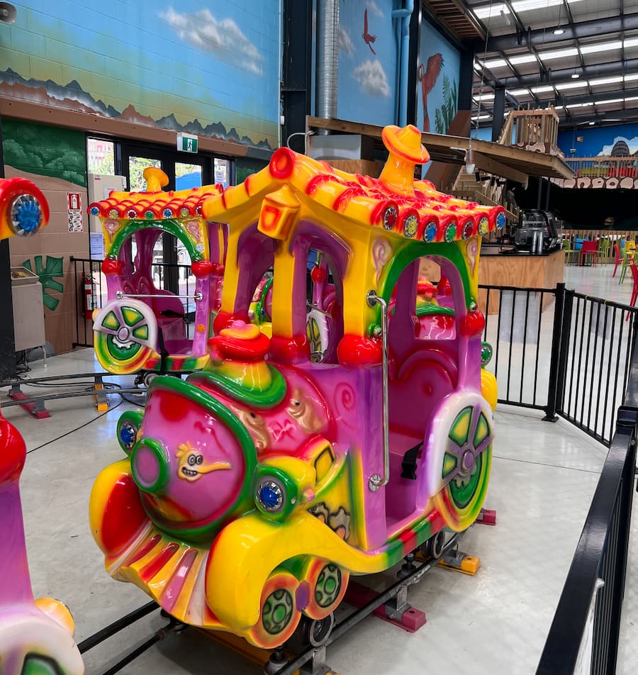 Colorful train-themed ride in an indoor amusement park setting